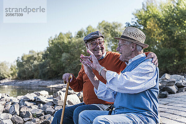 Active senior man discussing and enjoying with friend at riverside