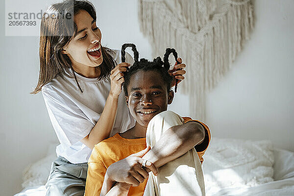 Playful girlfriend playing with boyfriend's hair at home