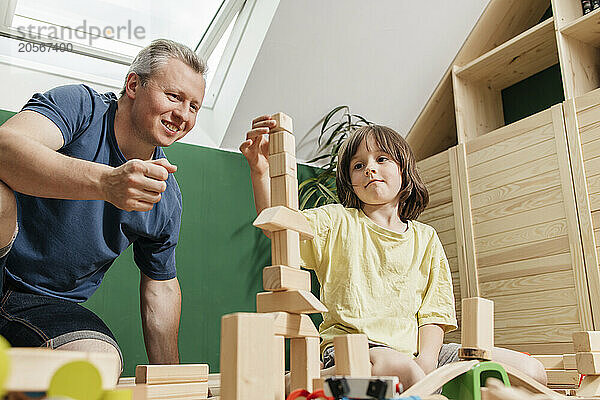 Boy stacking toy block with father at home