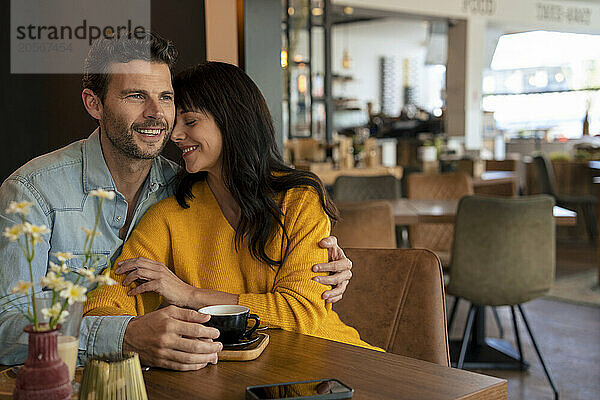 Loving couple sitting with coffee cup at table in cafe