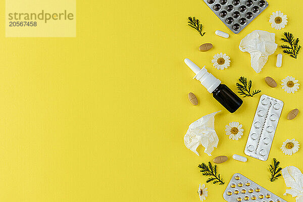 Medicines and chamomile flowers on yellow background