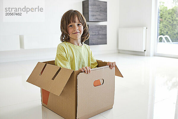 Cute boy in cardboard box at new apartment