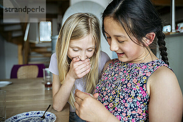 Smiling multiracial girls playing at dining table in home