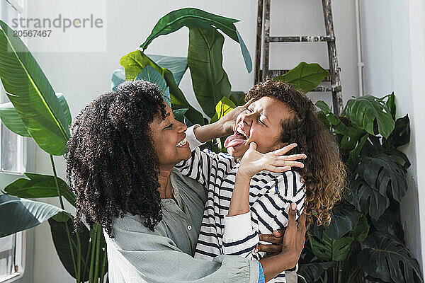 Girl pulling funny faces with mother at home