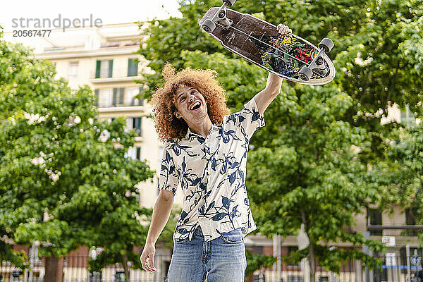 Happy man with skateboard standing in park