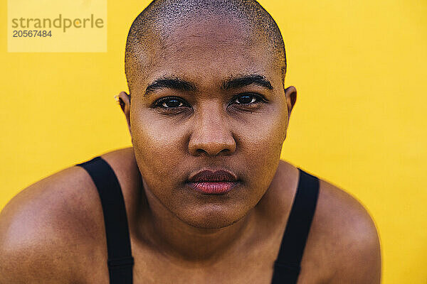 Bald woman in front of yellow wall