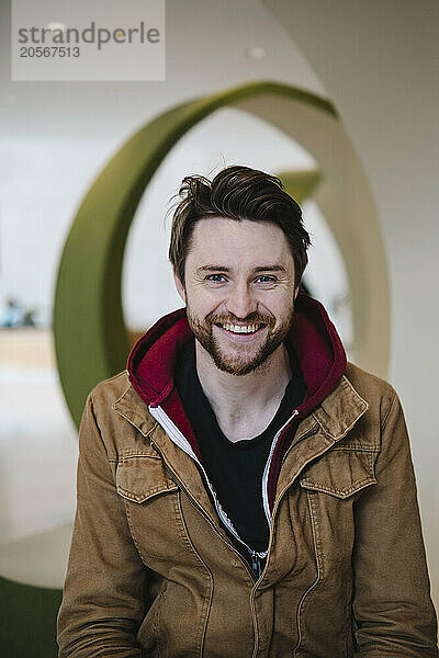 Happy man in brown jacket at lobby