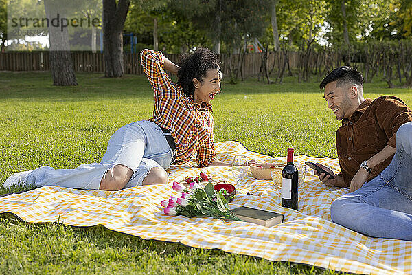 Happy couple relaxing on picnic blanket in public park