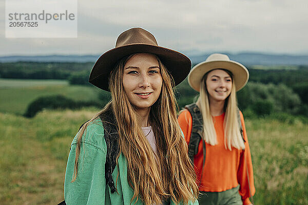 Smiling friends wearing hats and hiking on mountains in Poland