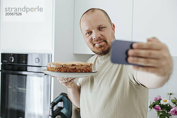 Man showing cake on video call through smart phone at home