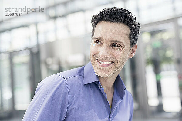 Happy mature businessman looking away in airport