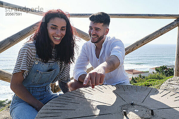 Happy couple enjoying sitting near sundial