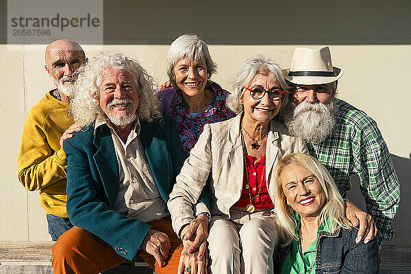 Happy retired women and men in front of wall on sunny day