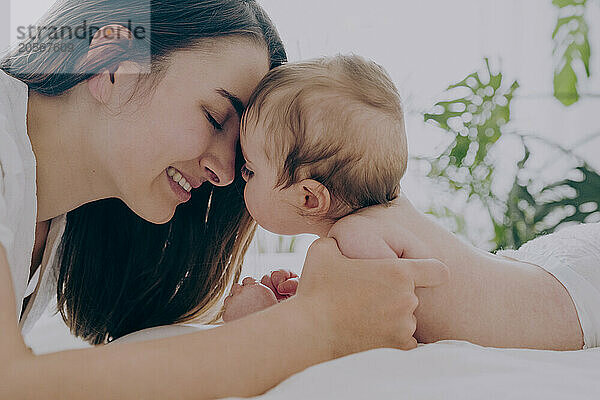 Affectionate mother with baby boy lying on bed at home