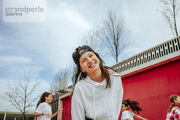 Cheerful teenage girl with friends at playground