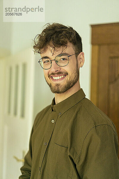 Smiling young handsome man wearing eyeglasses at home