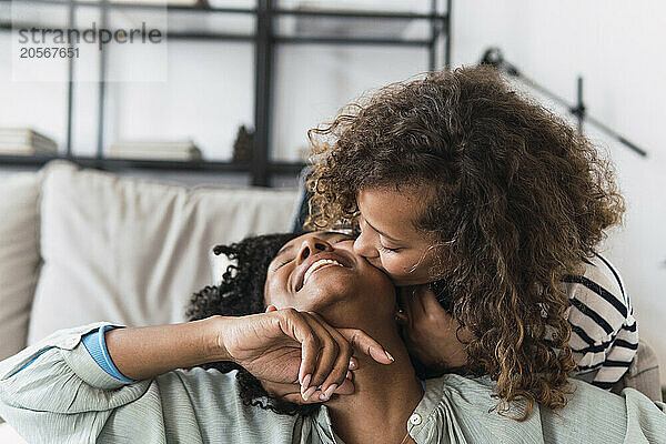 Daughter kissing smiling mother on the cheek