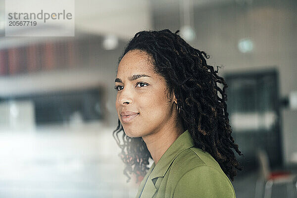 Young businesswoman with black dreadlocks looking away in office