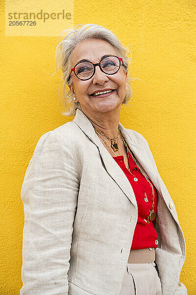 Smiling elderly woman in front of yellow wall