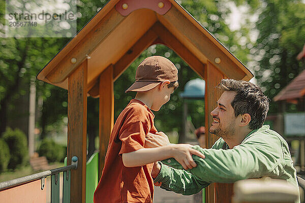 Smiling father tickling son at playground