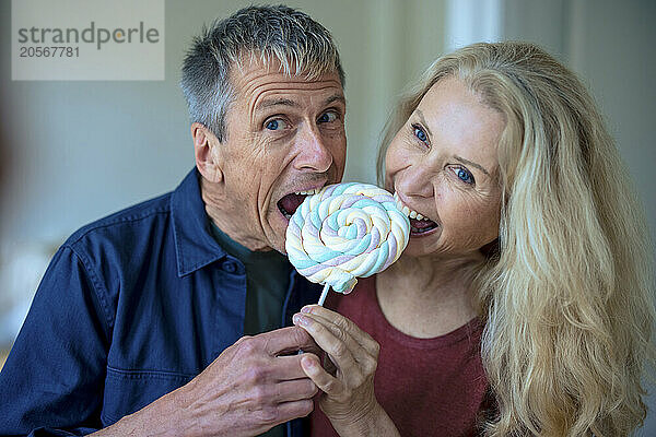 Retired senior couple eating candy lollipop