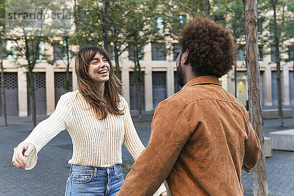 Happy woman with arms outstretched greeting boyfriend with hug