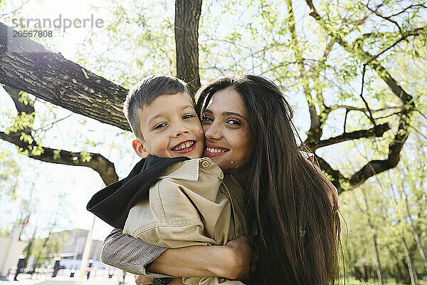 Happy long hair woman embracing son in park