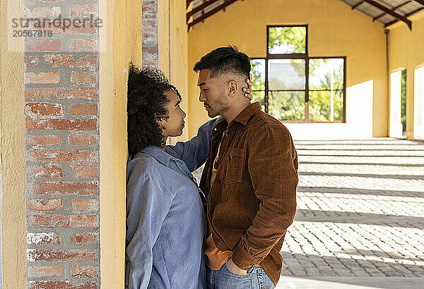 Affectionate woman leaning on wall and standing with boyfriend