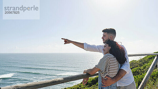 Man and woman looking at sea standing near railing