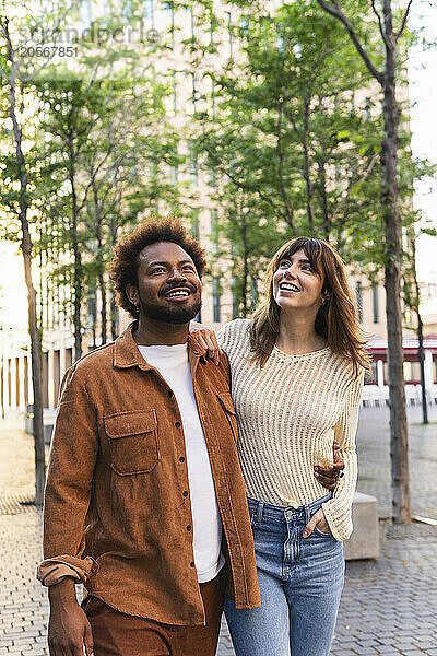 Smiling multiracial couple walking with arms around