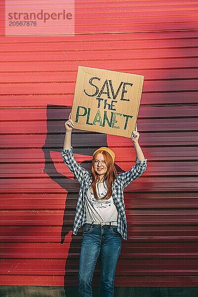 Young teenage girl protesting in front of red corrugated iron