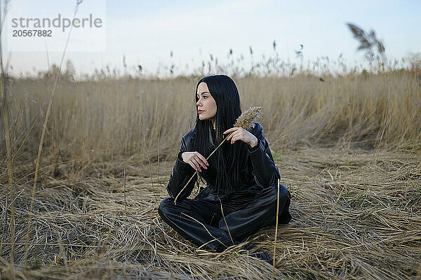 Beautiful woman sitting in reeds at field