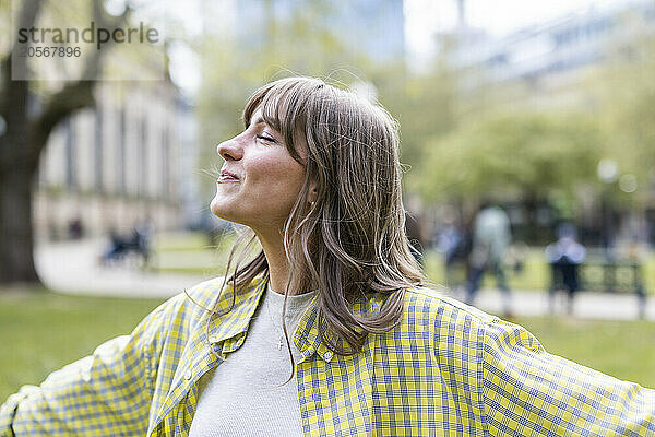 Smiling beautiful young woman with eyes closed at park