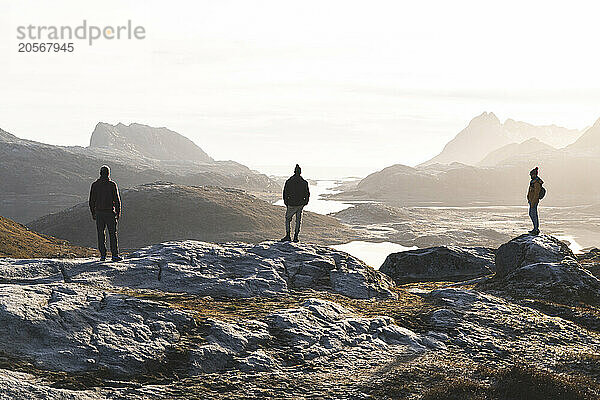 Friends standing on rocks in front of mountains at Lofoten and Nordic islands in Norway