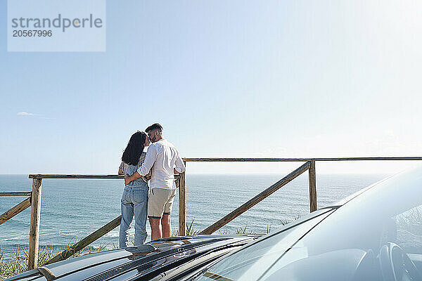 Boyfriend and girlfriend kissing each other standing near railing