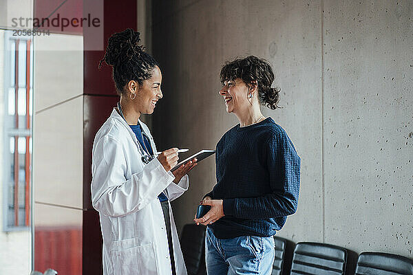 Happy doctor discussing with patient in hospital