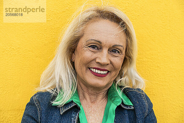 Happy elderly woman in front of wall