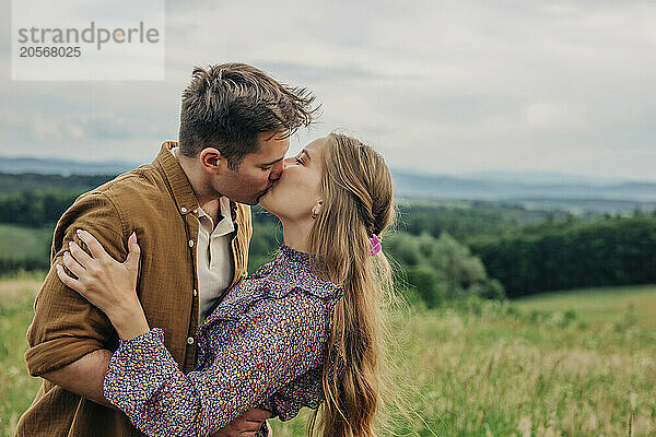 Young couple kissing in meadow on mountain