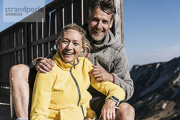 Happy woman sitting with boyfriend near wooden fence