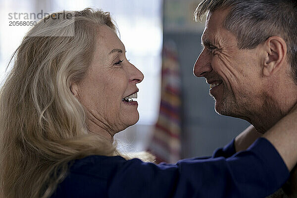 Happy retired loving senior woman face to face with man at home