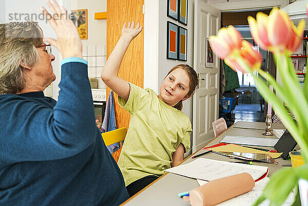 Grandmother and grandson giving high-five at home