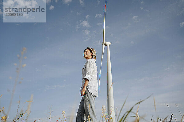 Smiling woman standing near windmill at wind farm