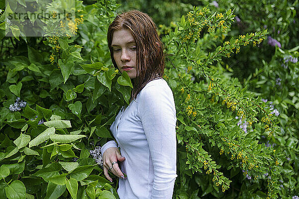 Young woman standing between plants at forest