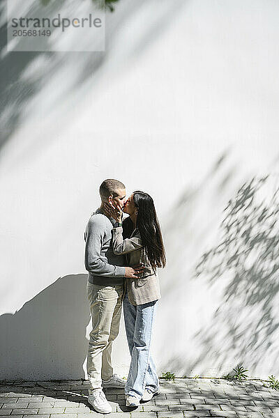 Romantic couple kissing and standing near wall