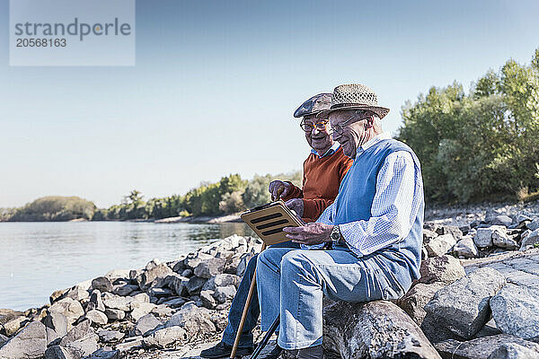 Senior friends using tablet PC at riverside