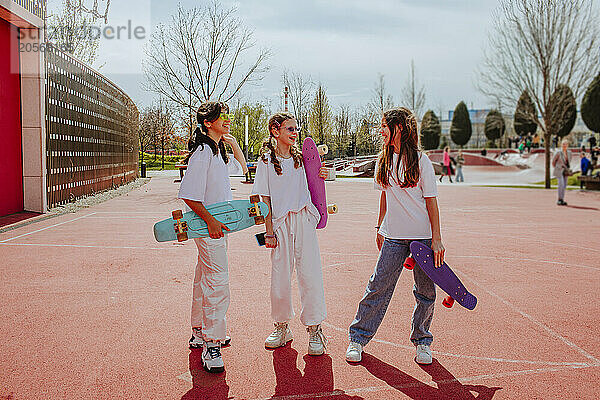 Teenage friends with skateboard discussing at playground