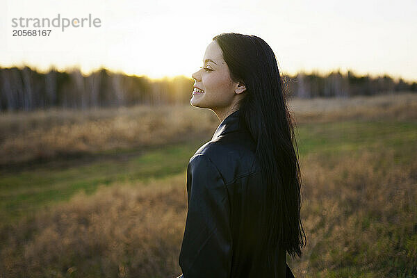 Smiling woman enjoying in field on sunny day