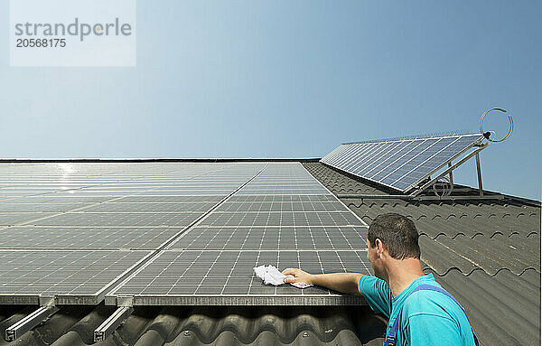 Farmer cleaning solar panels under clear sky