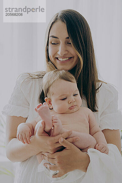 Happy mother with long hair holding son at home