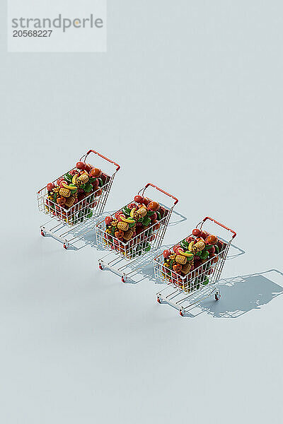 Shopping carts filled with colorful fruits and vegetables against blue background